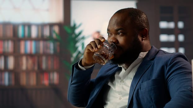 Black gentleman serving a glass of whiskey bourbon at the vintage social club, meeting with friends from the high class society to discuss business or estates. Old money entertainment. Camera B.
