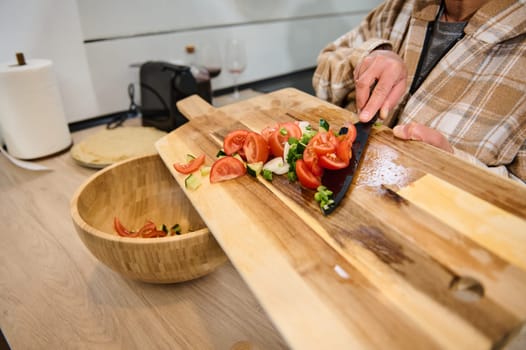 Freshly chopped vegetables being transferred from a cutting board into a wooden salad bowl, capturing the essence of healthy eating and home cooking in a cozy kitchen environment.