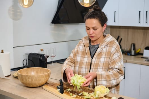 A woman is seen preparing a fresh salad on the countertop of a modern and cozy kitchen. The vibrant and cheerful ambiance emphasizes healthy eating and the joy of home cooking.