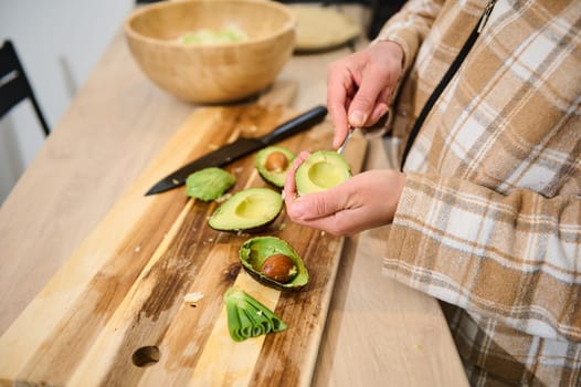 A hands-on moment in food preparation as a person prepares fresh avocado on a wooden cutting surface, illustrating homemade and healthy cooking in a cozy, inviting kitchen environment.