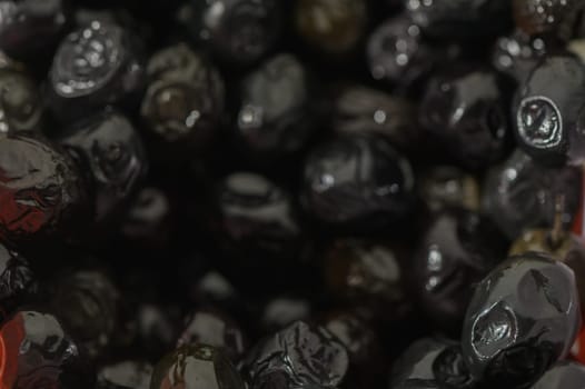 Silky black olives glisten in a vintage bowl, inviting culinary creativity. Their rich textures suggest an upcoming feast centered on vibrant flavors and shared enjoyment.