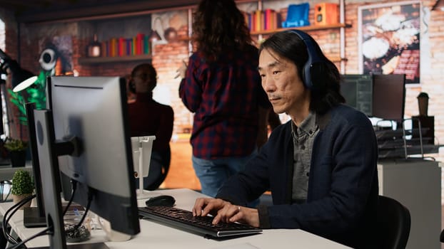 AI startup office chief technology officer listening music while coding application. Senior programmer wearing headphones while working in artificial intelligence software development agency, camera A