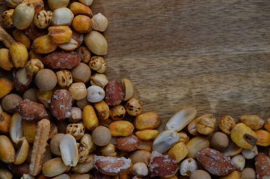 A delightful assortment of various nuts and seeds is spread across a rustic wooden surface, showcasing an array of colors, sizes, and textures that evoke a sense of natural beauty and warmth.