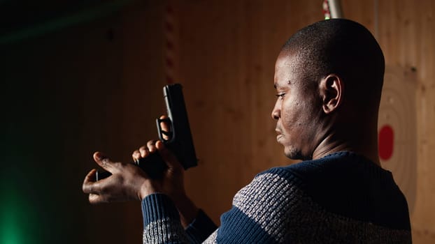 Shooting range customer reloading pistol, preparing to shoot targets during recreational sport activity. Man at firing range location loading pistol with ammunition, camera A close up