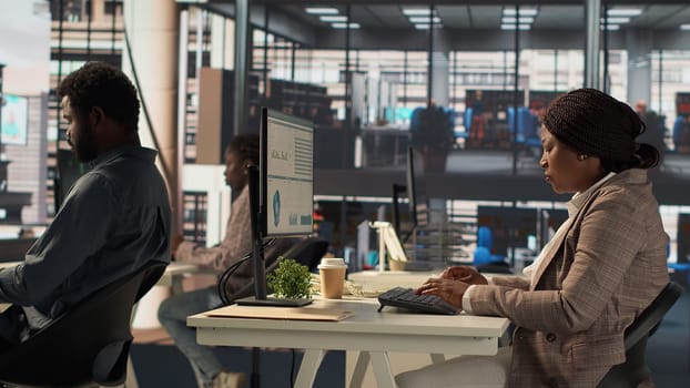 Skilled female investor working on financial forecasts at her workstation, using monthly infographics data to manage business tasks for enterprise development. Company goals. Camera A.