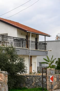 A cozy house features a lovely balcony adorned with greenery, nestled in a peaceful urban area during daylight.