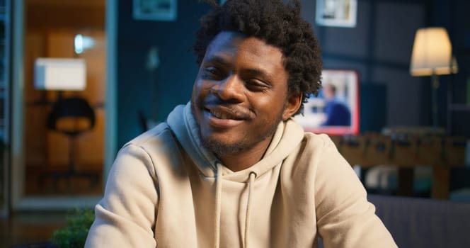 African American adult enjoying the comfort of his loft apartment while working remotely on his laptop. An excellent representation of productivity and modern work from home trends. Camera B.