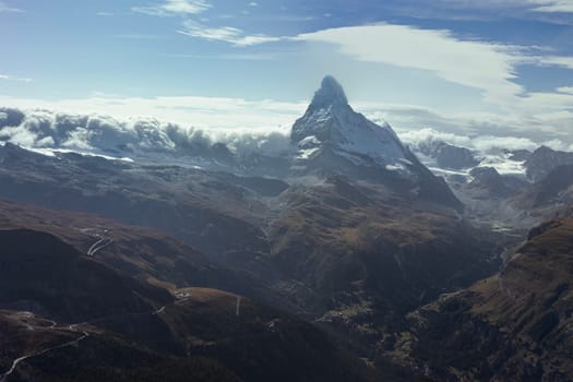 Swiss landscape photograph of the mountain range near Zermatt, with the iconic Matterhorn towering over beautiful valleys in an alpine scene. Real photo