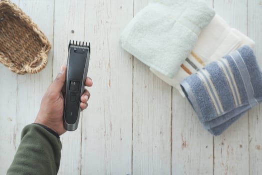 A person is preparing to groom hair using a hair clipper next to towels.