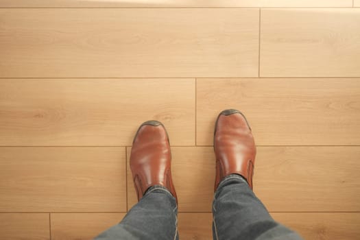 Brown boots stand on a smooth wooden floor illuminated by sunlight.