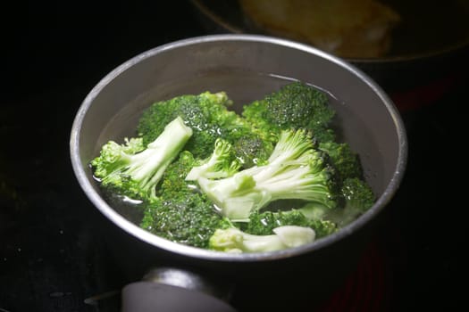 Fresh broccoli is boiling in a pot on the stove, ready to be served.