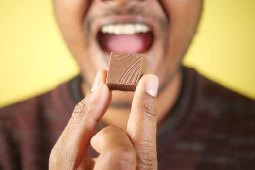 A joyful person holds up a chocolate piece, exuding excitement and delight.
