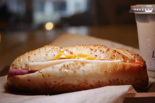 Tasty sandwich with cheese and ham sitting on a wooden surface.