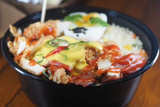 Savory chicken bowl featuring rice, fresh vegetables, and sauces.