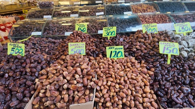 Different types of dates are showcased at a market stall under bright lights.