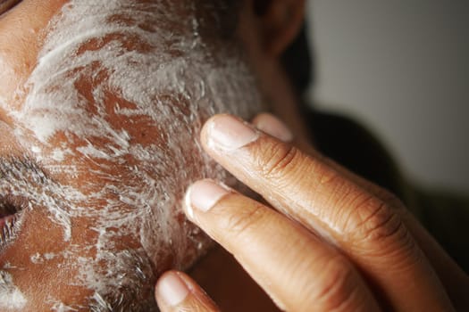 Cleansing product is applied to the man's face as part of his skincare.