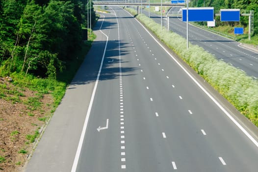 An empty, well-maintained highway surrounded by vibrant greenery, capturing the beauty of transportation infrastructure and the serenity of the environment it integrates with.