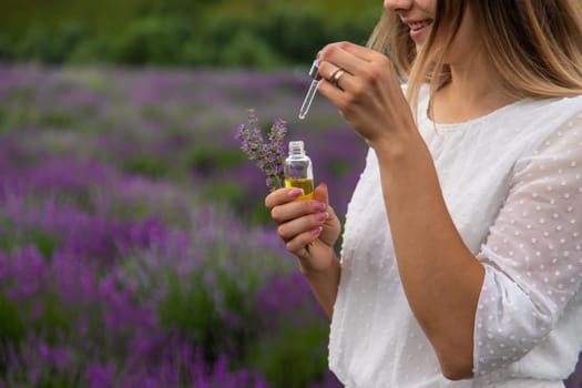 Woman in lavender field holding essential oil in her hands