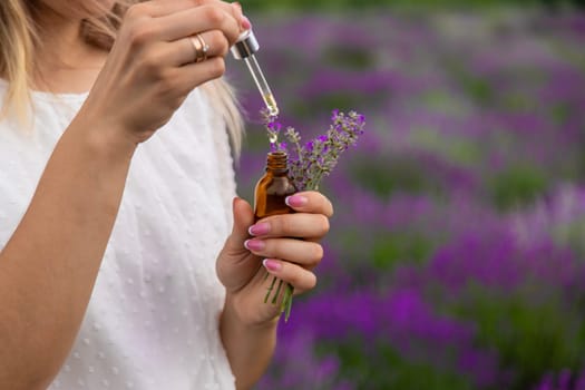 Woman in lavender field holding essential oil in her hands