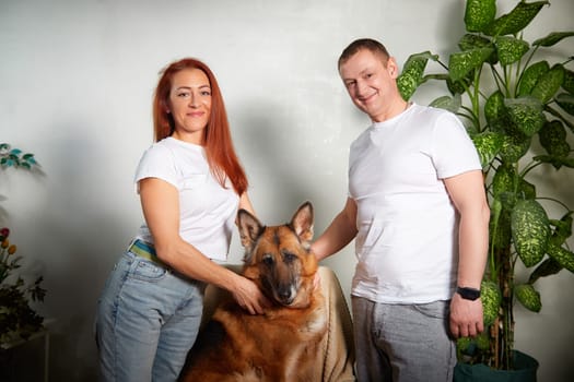 A couple gently interacts with their German Shepherd dog while relaxing in their warm, inviting living space.