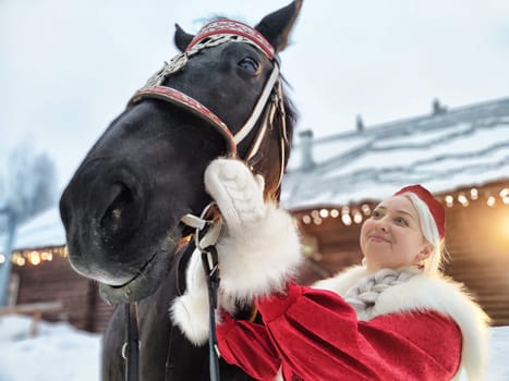 A beautiful girl dressed in traditional Russian attire enjoys a festive photoshoot with a horse during Maslenitsa.