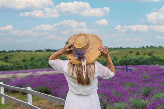 Woman in lavender field. Happy carefree woman in white dress and straw hat walking through lavender field