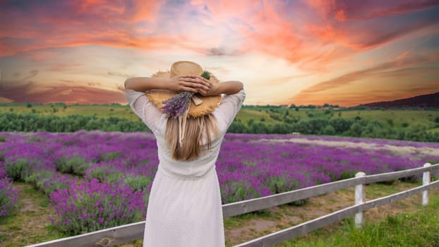 Woman in lavender field. Happy carefree woman in white dress and straw hat walking through lavender field