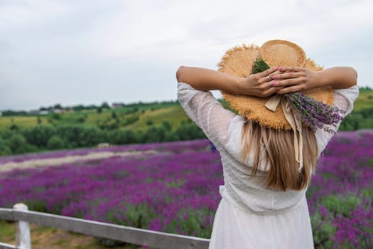 Woman in lavender field. Happy carefree woman in white dress and straw hat walking through lavender field