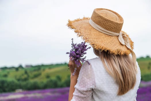 Woman in lavender field. Happy carefree woman in white dress and straw hat walking through lavender field