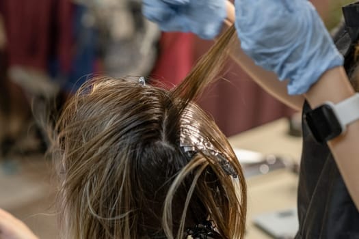 A stylist applies dye to a clients roots in a modern salon, capturing a moment of creativity and transformation.