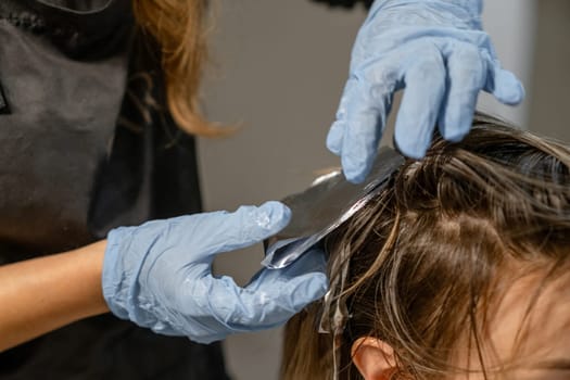 Stylist applies foil highlights to clients hair in a salon, showcasing the hair coloring process during a professional treatment.
