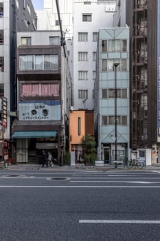People walking on the sidewalk in tokyo, japan, passing buildings and shops