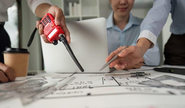 A team actively collaborates and communicates about architectural plans using walkie-talkies to enhance information flow and project coordination.