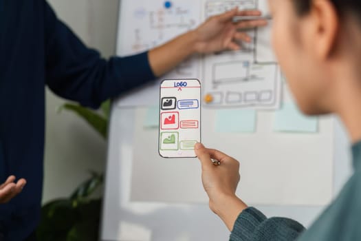 In a creative brainstorming session, a team member showcases a colorful mobile app prototype, engaging colleagues in a discussion about the design's features and functionality.