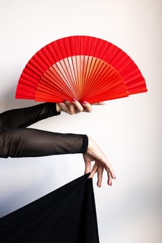 Elegant display of red asian fan in female hands with black dress and sheer sleeves.