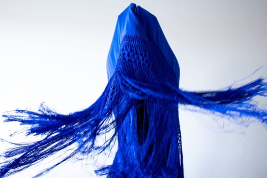 Abstract blue fabric art with dynamic fringes and geometric shapes.