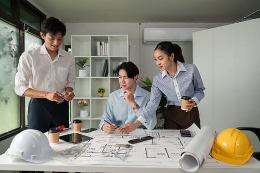 Three professionals collaborate on architectural designs and project plans, fostering teamwork and innovation in a modern workspace.