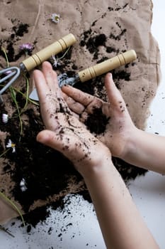 Caucasian child engaging in gardening with tools and soil indoors.