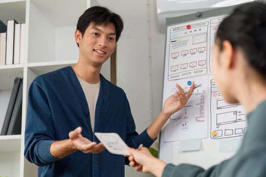 A designer engages with team members during a presentation on UX design concepts, showcasing wireframes, challenges, and possible solutions for projects.