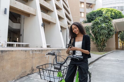 A stylish young woman engages with her smartphone next to her bicycle, embodying a sustainable urban lifestyle and modern connectivity, promoting eco-friendly transportation.