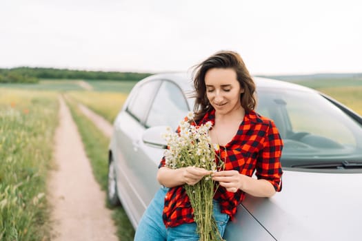 A woman is sitting on the side of a road with a bouquet of flowers in her hand