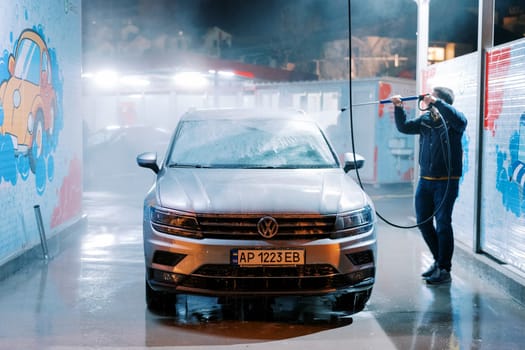 Driver washing a car with a hose at a self-service car wash. High quality photo