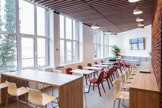 This room features a long table surrounded by numerous chairs. The chairs are set up in an orderly fashion, ready for a meeting or event. The room is well-lit and spacious, creating a professional and organized atmosphere.