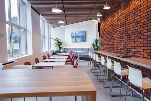 The room is densely packed with numerous tables and chairs, creating a busy and functional space for gatherings or events. The tables are varied in size and shape, while the chairs are lined up neatly around them, suggesting a planned arrangement for seating.