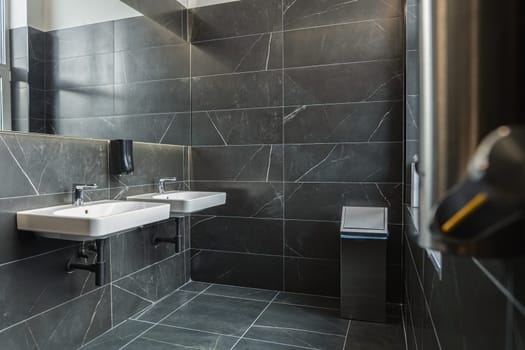 This is a modern toilet featuring a sleek sink and a large mirror mounted above it. The sink is made of white ceramic with chrome fixtures, and the mirror extends from wall to wall. The room is well-lit, creating a bright and functional space.