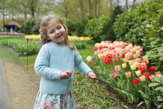 Happy girl laughs in a park with the tulips