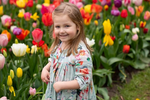 Happy girl laughs in a park with the tulips