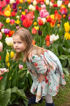Happy girl laughs in a park with the tulips