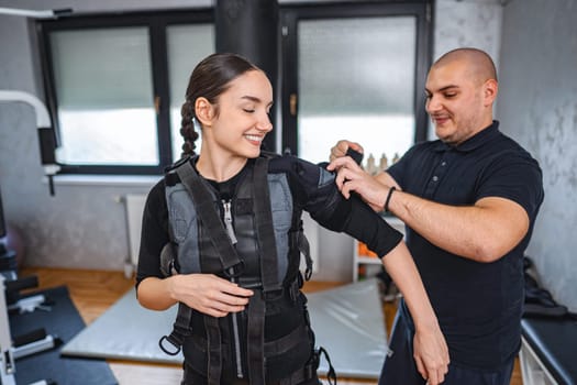 A person is adjusting fitness equipment on an individual preparing for training.