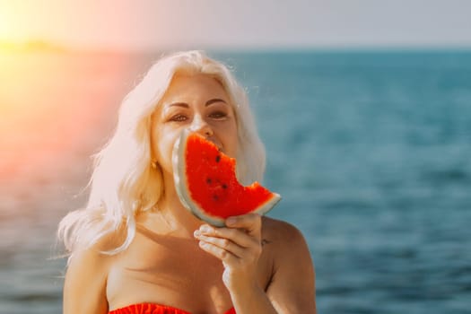 Blond woman in red bikini holds a juicy watermelon slice, partially obscuring her face, against a bright blue ocean backdrop. Summer vibes.